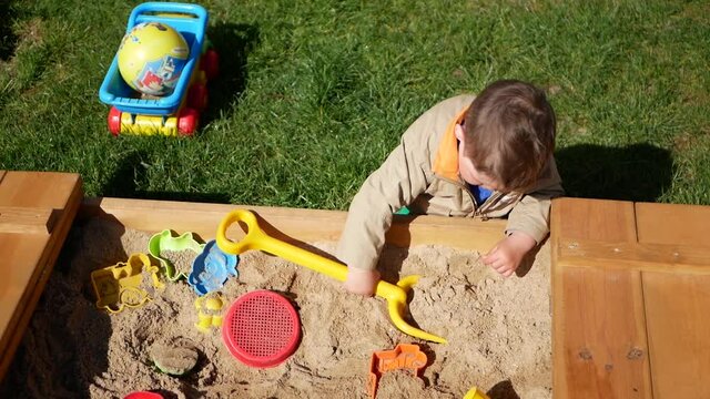 1-2 year old boy plays in the sandbox. A child spends time playing in the sandbox