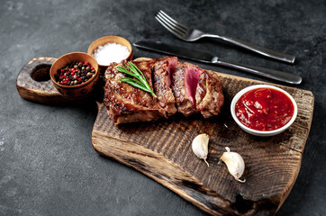 
Grilled beef steak with spices served on a cutting board on a stone background