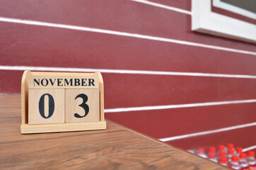 November 3, Number cube with wooden table beside the wall.