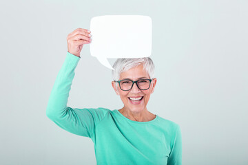 Happy mature woman in plain blue long sleeve t-shirt holding empty speech bubble isolated on...