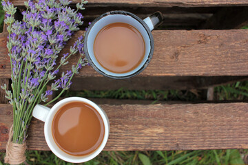 Two Cups of coffee with milk or cappuccino and lavender flowers on wooden board in summer garden. Enjoying morning coffee. Top view, copy space. Selective focus