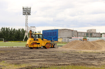 Large road-roller paving a road at the stadium. Road construction