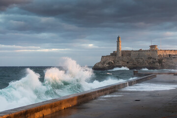Big waves on Malecon streets during sunrise with storm clouds in background. Havana, Cuba