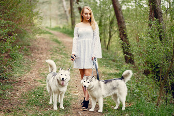 Beautiful girl in a white dress. Woman in a summer park. Lady with a dog