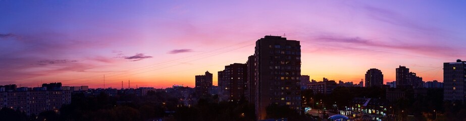 Pink orange purple sunset over the city. Multicolored sky and black silhouette of tall buildings of the metropolis