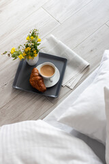 breakfast in bed, tray with cup of coffee, french croissant, newspaper and flowers in the morning,...