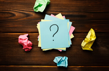 Paper stickers with a question mark on a wooden background