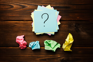 Paper stickers with a question mark on a wooden background