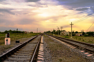 Fototapeta na wymiar Railway at sunset. Railroad station. Railroad crossing. Railway signs at the crossroads. Sky with rain clouds at sunset. Clouds in the sky. Rails, sleepers, stones. Perspective. Horizon