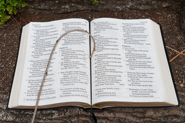 Naklejka na ściany i meble Holy Bible open with small staff on top. Highlighting Psalm 23. Close-up. Outdoors on stair step.