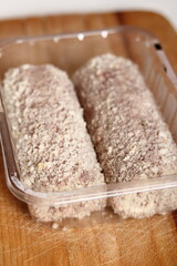 Uncooked meat roulade in plastic tray. Rolled meat with a filling of cheese and ham.