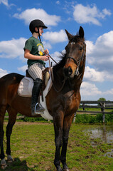 Obraz premium Teenage girl resting her thoroughbred horse in a corral after a trail ride