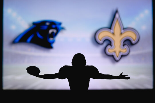 Carolina Panthers Vs. New Orleans Saints. NFL Game. American Football League Match. Silhouette Of Professional Player Celebrate Touch Down. Screen In Background.