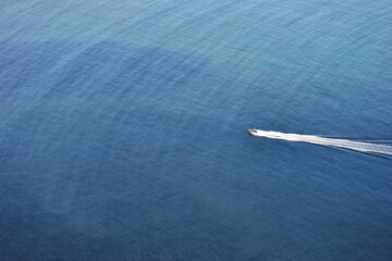 Speedboat leaving white trail on vast blue ocean 