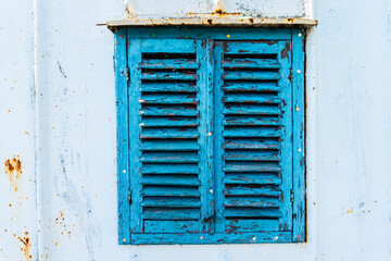 Old wooden window painted blue with rusty lock. Texture, wall of an old wooden house with shuttered windows, painted blue. 