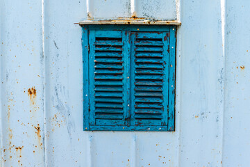 Old wooden window painted blue with rusty lock. Texture, wall of an old wooden house with shuttered windows, painted blue. 