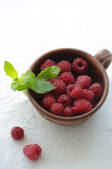 On a white background is a cup with raspberries.
