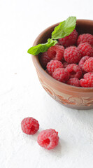 On a white background is a cup with raspberries.
