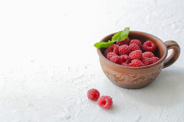 On a white background is a cup with raspberries.
