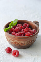 On a white background is a cup with raspberries.
