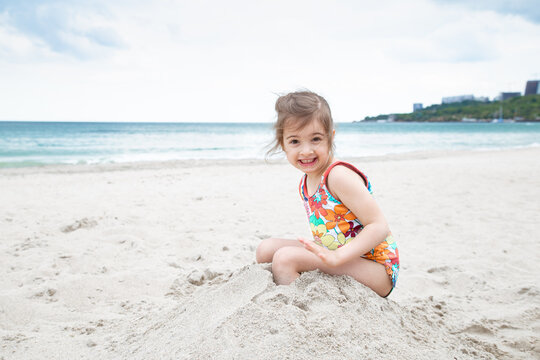 Little cute girl playing in the sand on the beach by the sea