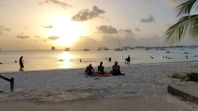 Black people sitting talking enjoying sunset at the beach in beautiful Barbados, Caribbean. Island scenes and silhouettes 