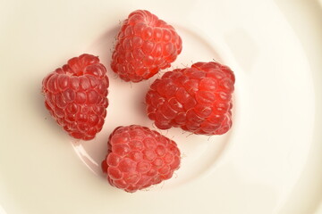Juicy organic raspberries, close-up, on a ceramic plate.