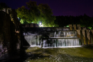 Night summer European park with river and waterfall. 10 July 2020 Minsk Belarus