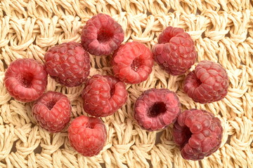 Juicy organic raspberries, close-up, on a straw mat.
