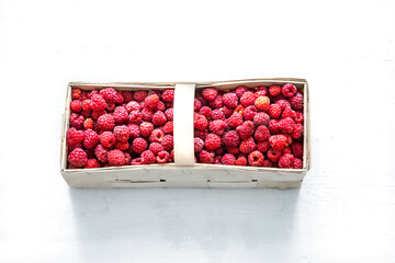 basket with fresh raspberries on a light background