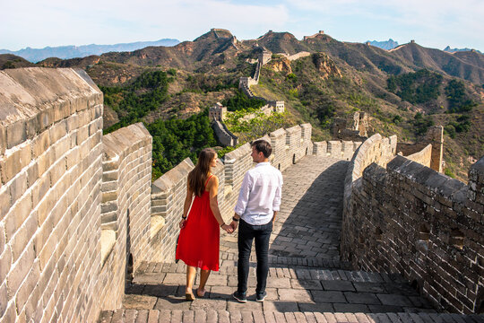 Scenic view of young couple holding hands on restored part of the Great Wall of China, Jinshanling - Powered by Adobe