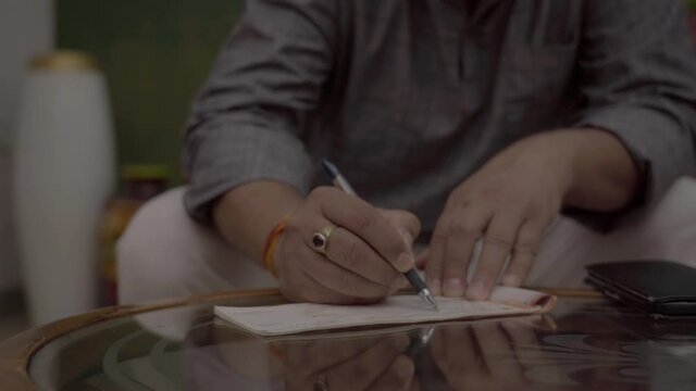 Indian men filling, signing cheque, hands of man. 