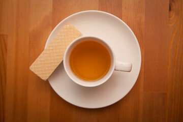 Tea cup and wafer snack on the wooden table. Tip view