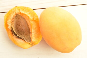 Juicy organic apricots, close-up, on a white wooden table.