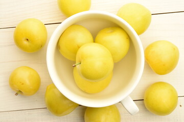 Ripe yellow plum, close-up, on a white wooden table.