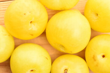 Ripe yellow plum, close-up, on a wooden table.