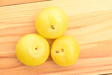 Ripe yellow plum, close-up, on a wooden table.