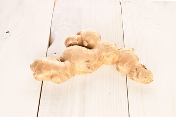 Fresh ginger root, close-up, on a white wooden table.