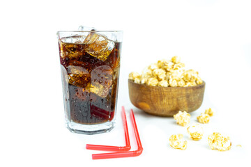 glass of cold refreshing cola soda with ice, wooden bowl of fresh popcorn with caramel
