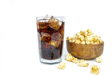 glass of cold refreshing cola soda with ice, wooden bowl of fresh popcorn with caramel