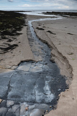 The tide has turned at Low Newton-by-the-Sea but clouds are heavy before the rain on a warm summers day.
