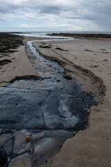 The tide has turned at Low Newton-by-the-Sea but clouds are heavy before the rain on a warm summers day.