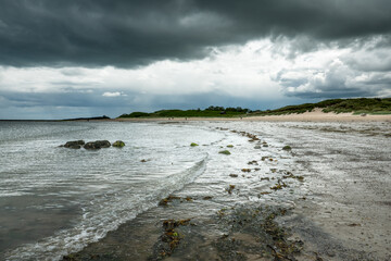 The tide has turned at Low Newton-by-the-Sea but clouds are heavy before the rain on a warm summers day.
