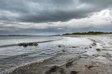 The tide has turned at Low Newton-by-the-Sea but clouds are heavy before the rain on a warm summers day.