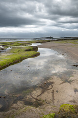 The tide has turned at Low Newton-by-the-Sea but clouds are heavy before the rain on a warm summers day.