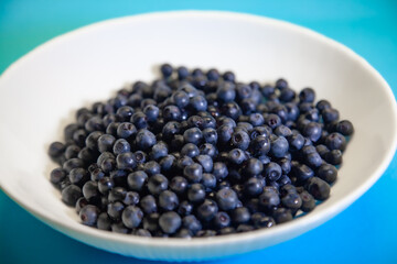 Spoon juicy blueberries in a white bowl