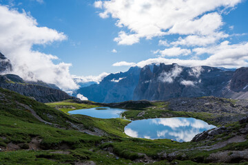 Fototapeta na wymiar Dolomites Alps. Lago dei Piani. Italy. Two alpine lakes on background of dolomite grey peak Crode dei Piani mountain wrapped by white clouds. Desert view