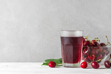 Cherry juice in a glass with fresh berries on white background. Refreshment summer drink