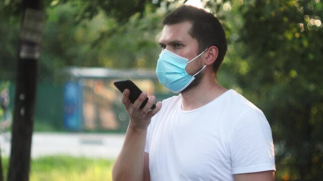 Student Freelancer Man Having Online Meeting On Street Voice Recognition Speech Recovery. Young Businessman In Medical Protective Face Mask Chatting On Phone While Coronavirus Quarantine Self