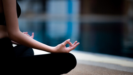 Meditation hands in lotus pose by the pool.